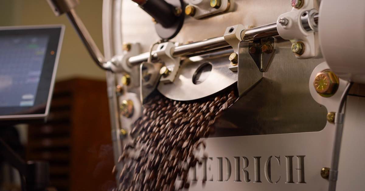 Close-up of freshly roasted coffee beans flowing from a coffee roasting machine at Coorg Wilderness Resort & Spa.